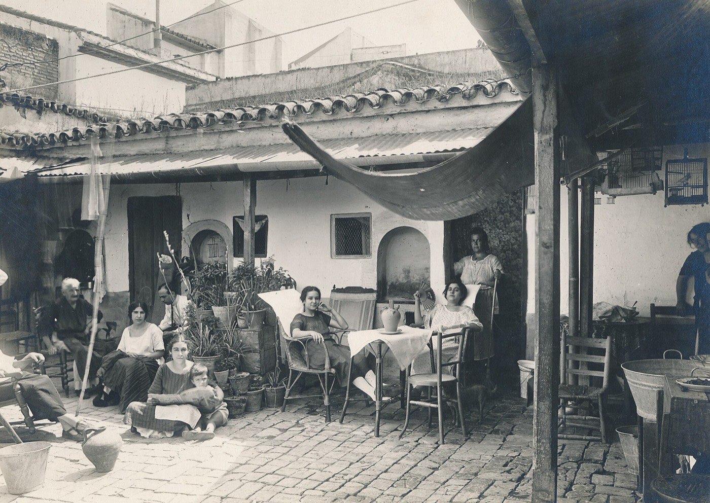 Neighbours sitting together in the cobbled courtyard of a shared house in Seville